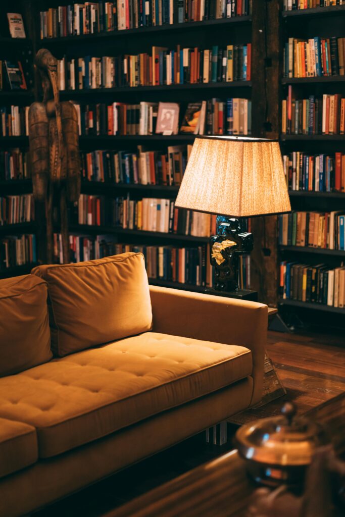 pexels photo 1907784 1907784 Warm and inviting library scene featuring a cozy couch, bookshelves, and a lamp for ambient lighting.